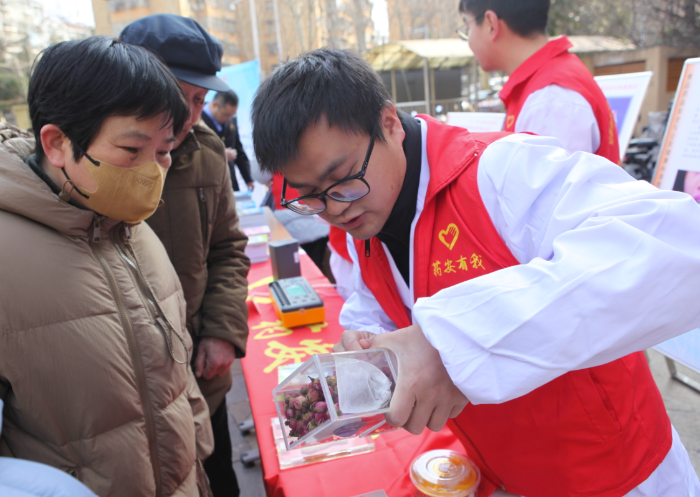 图为安徽省药监局青年志愿者为社区居民介绍常见中药材真伪鉴别技巧。